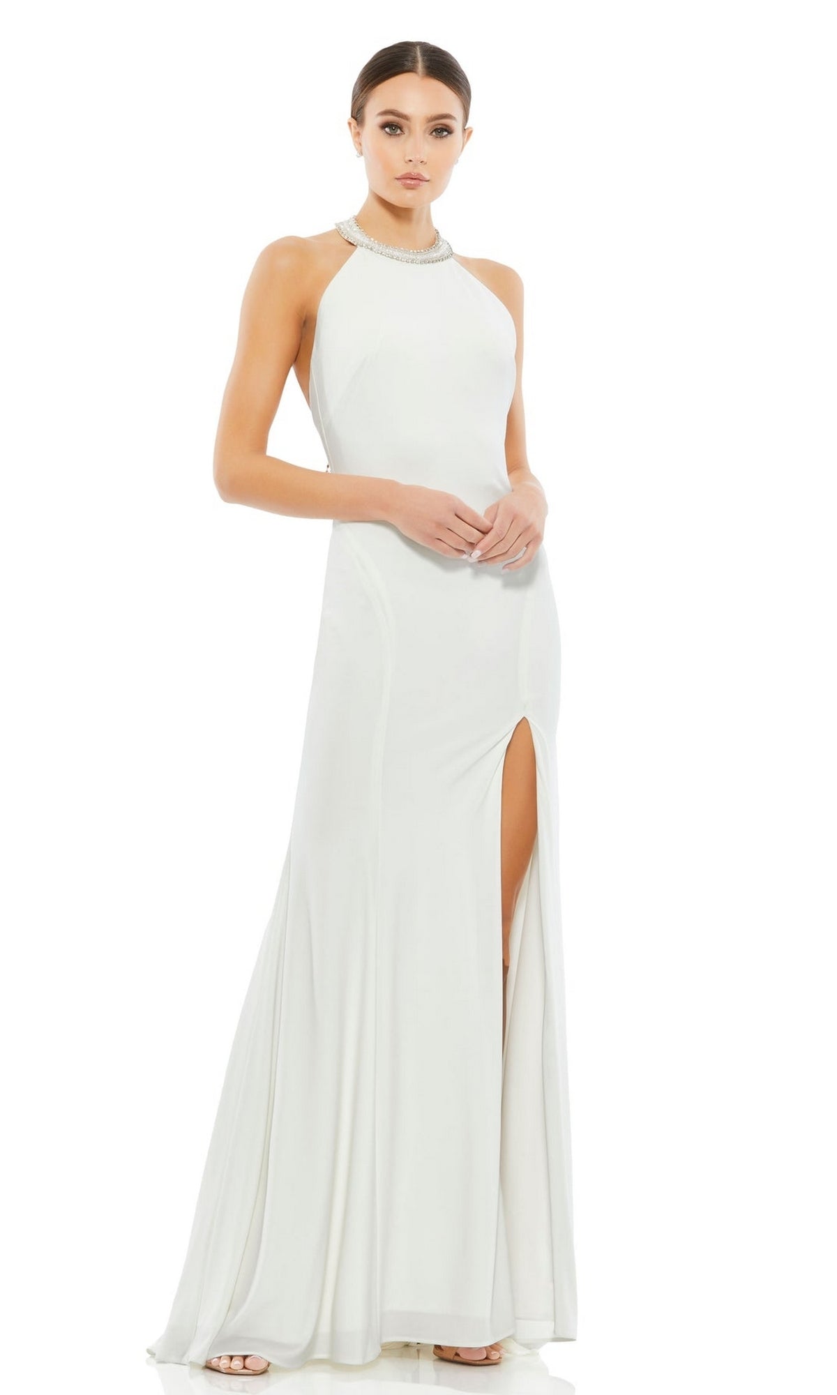 A woman models the Long Formal Dress 25572 by Mac Duggal— a sleeveless white halter neck gown with a fitted bodice, floor-length skirt, and side leg slit—against a plain white background.